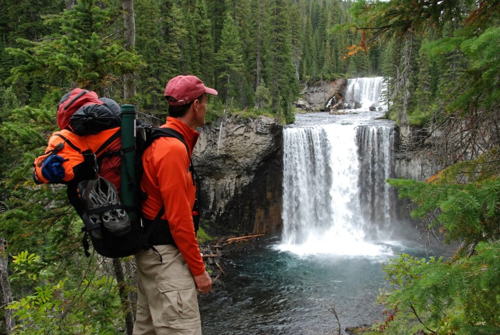A backpacker in Yellowstone looks at a waterfall