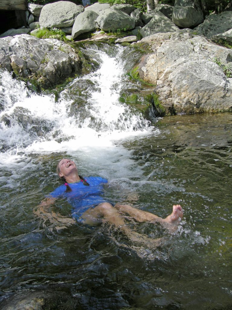A hiker floats in a mountain stream