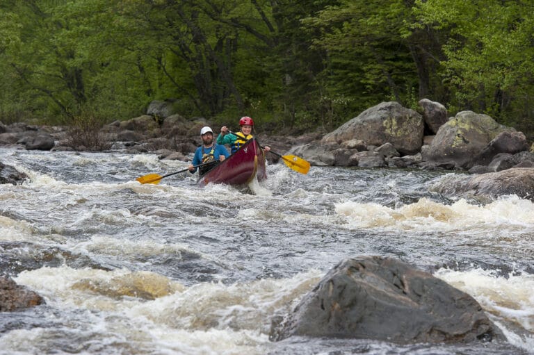 Two canoeists navigate a whitewater river