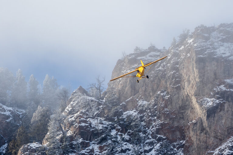 A small plane flies near a mountain