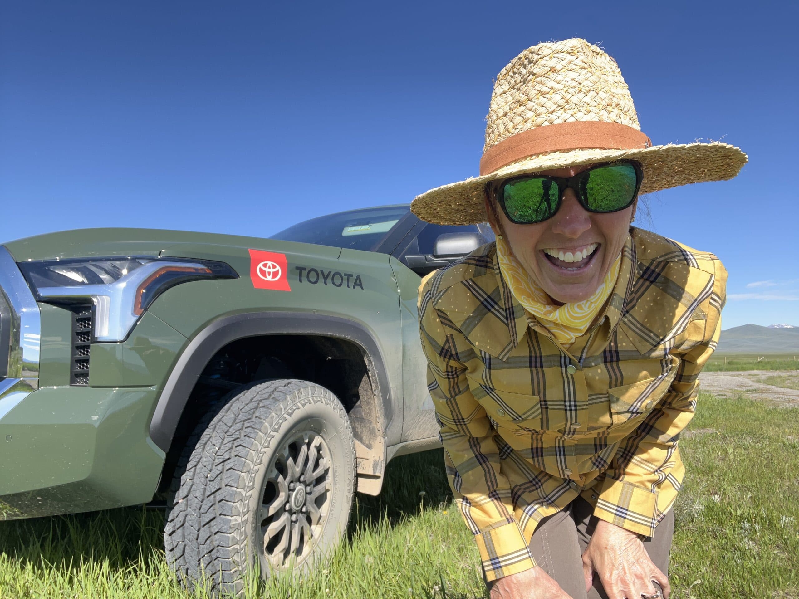 Kris Millgate standing in a field in Montana wearing a large sun hat. 