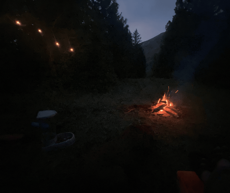 Solar lights hang at a Campsite at night with a small campfire