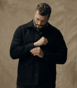 Man wearing a dark Filson - Mackinaw Wool Cruiser Jacket buttoning one of the sleeves. 